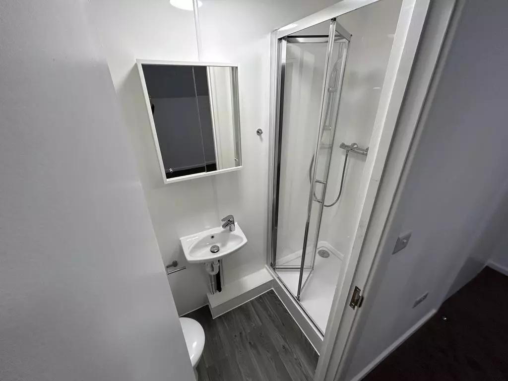 Bright, modern bathroom with a corner shower en...