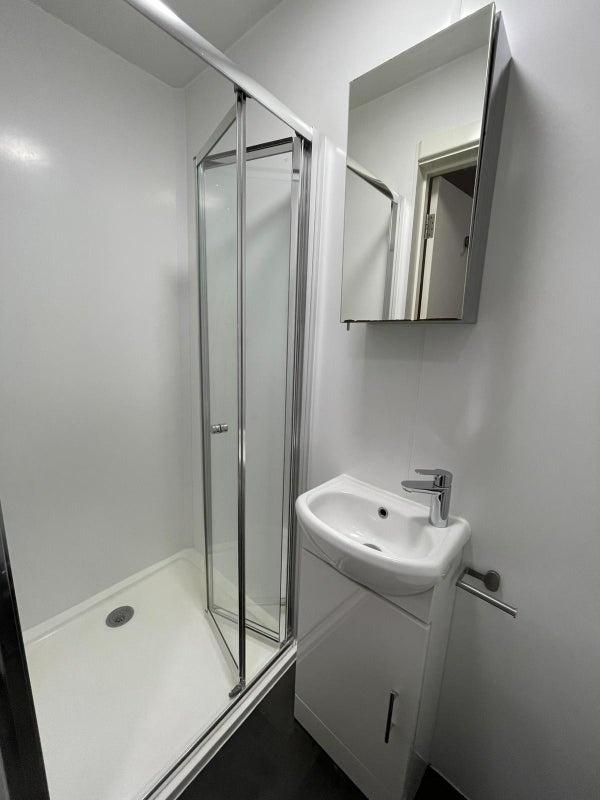 Bright, modern bathroom with a corner shower en...