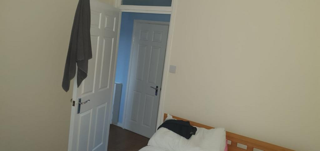 Compact bedroom with a simple wooden bed, neutr...