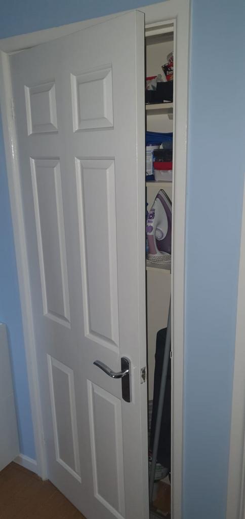 Narrow storage cupboard with shelving holding h...