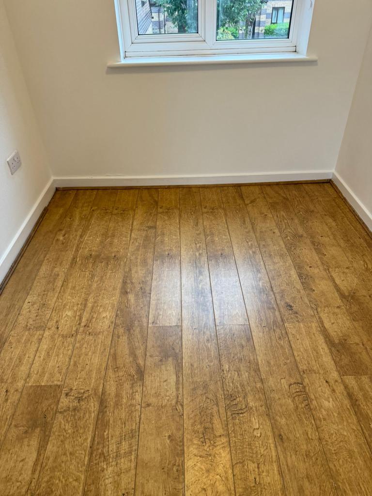 Bright room with warm wood-effect flooring and ...