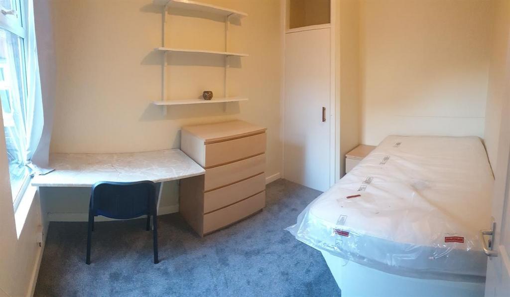 Bright, simply furnished bedroom with a bedside...