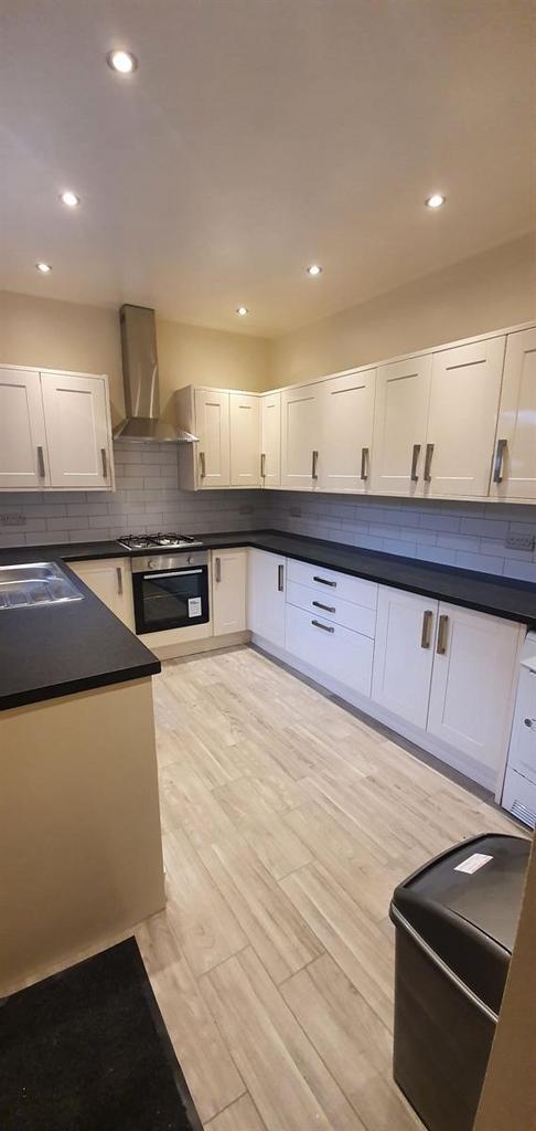 Bright modern galley kitchen with ample white c...