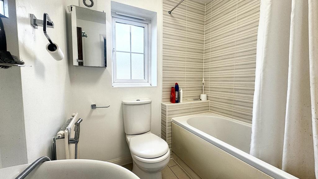 Bright, modern bathroom with a white bathtub, s...