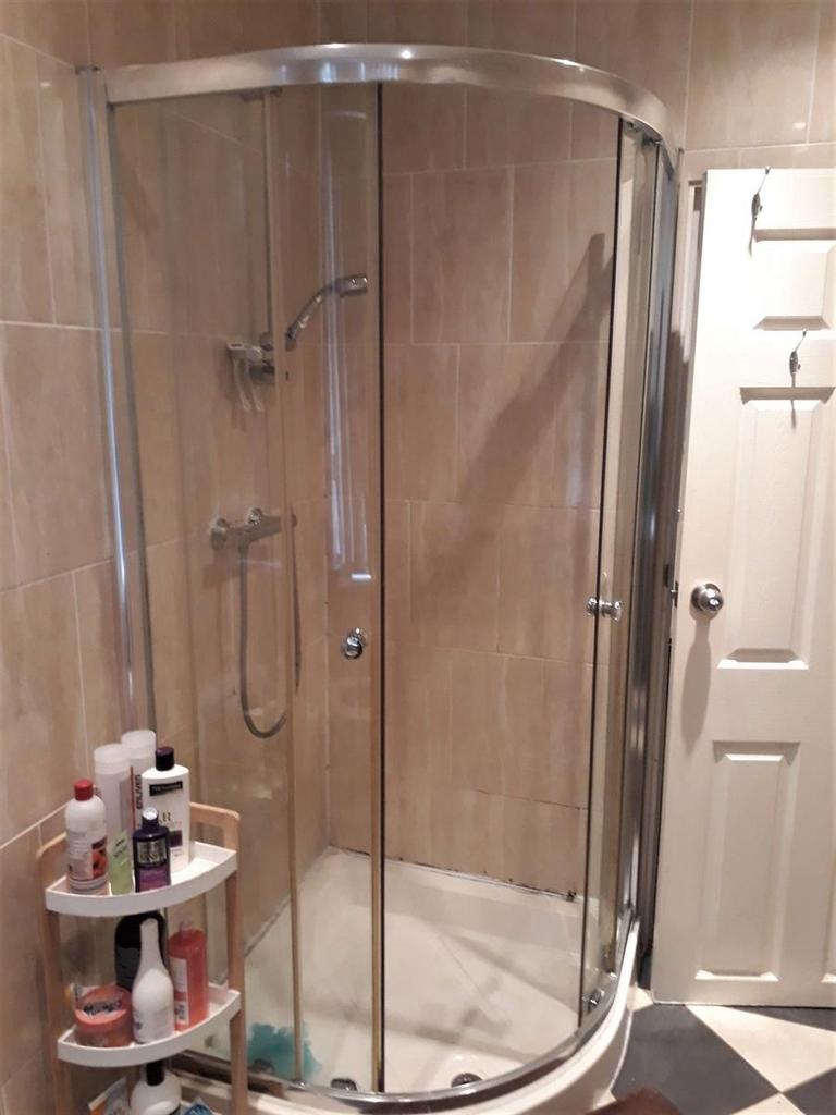 Modern tiled bathroom with a curved glass showe...