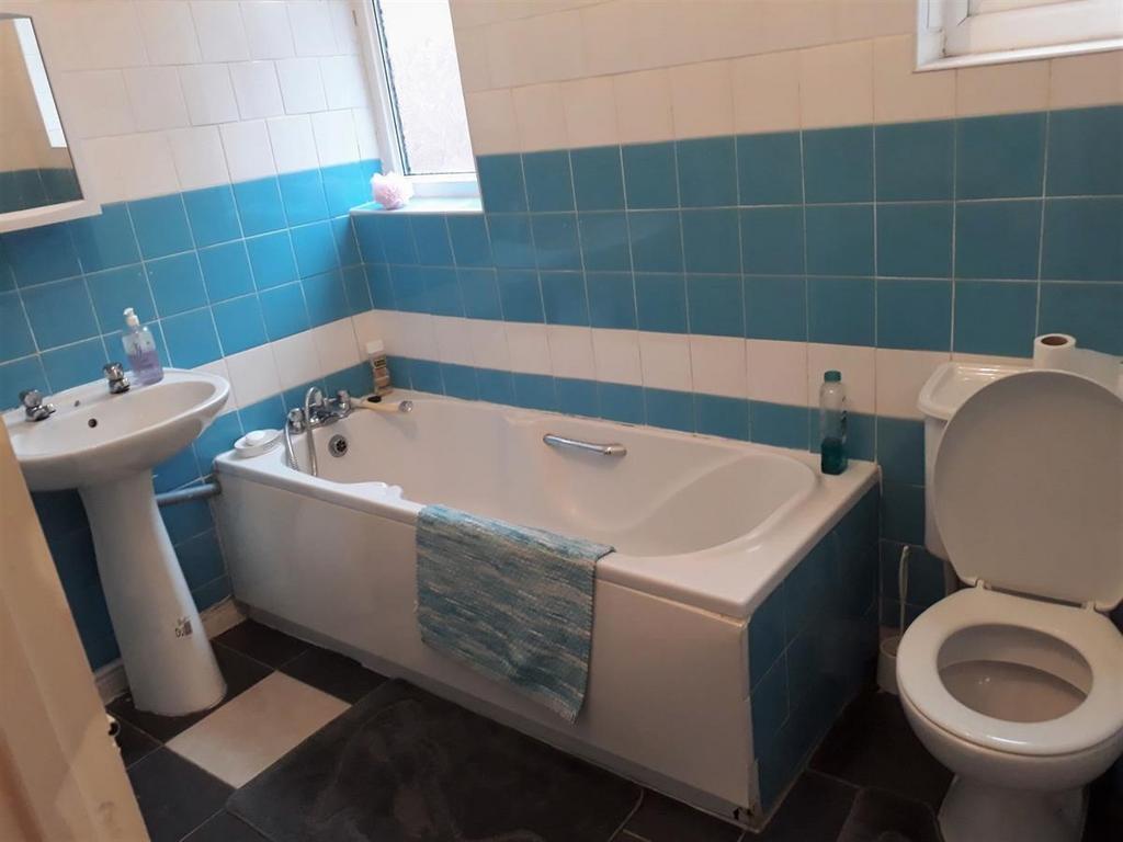Bright, tiled bathroom with a modern white bath...
