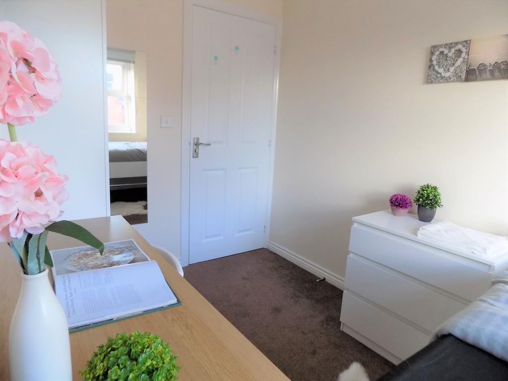 Bright, simply furnished bedroom with a tidy de...