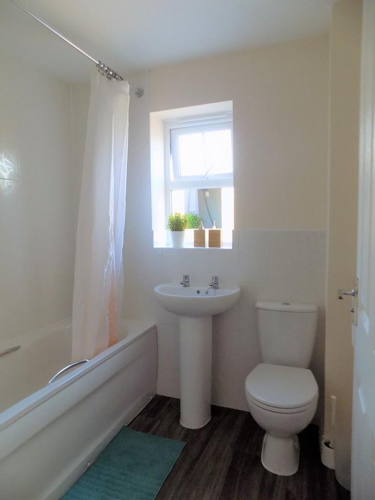 Bright, clean bathroom with a bathtub and showe...