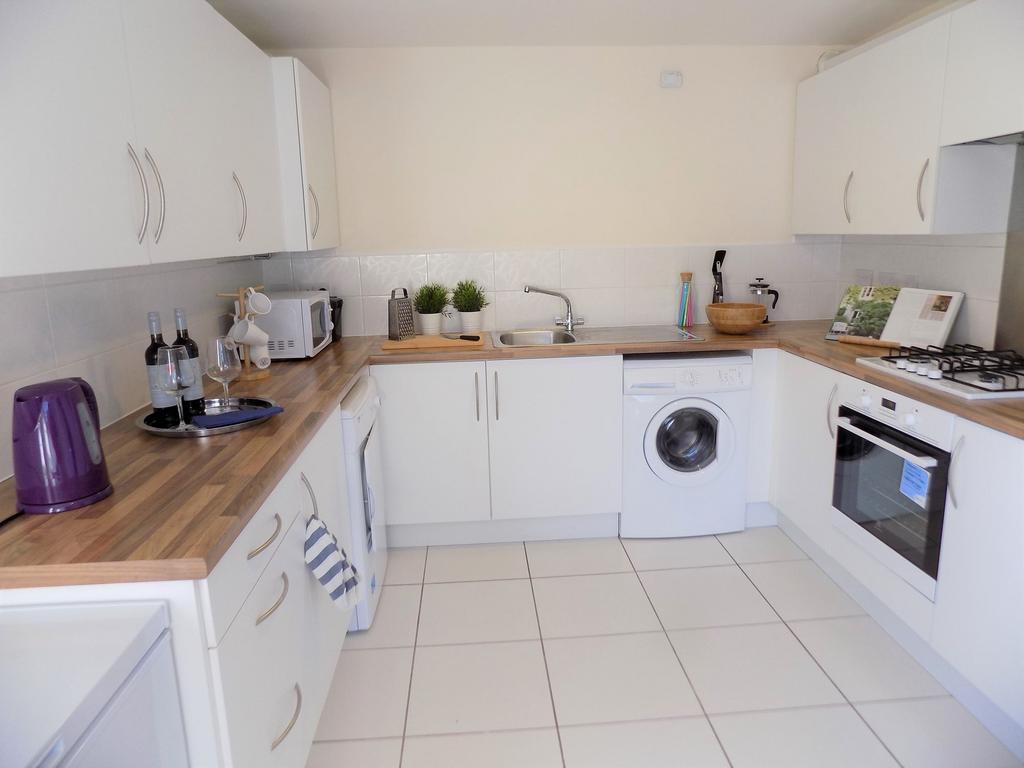Bright, modern galley kitchen with white cabine...