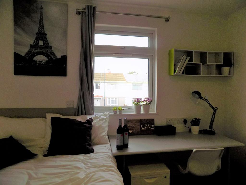 Bright, neatly styled bedroom with a desk by th...