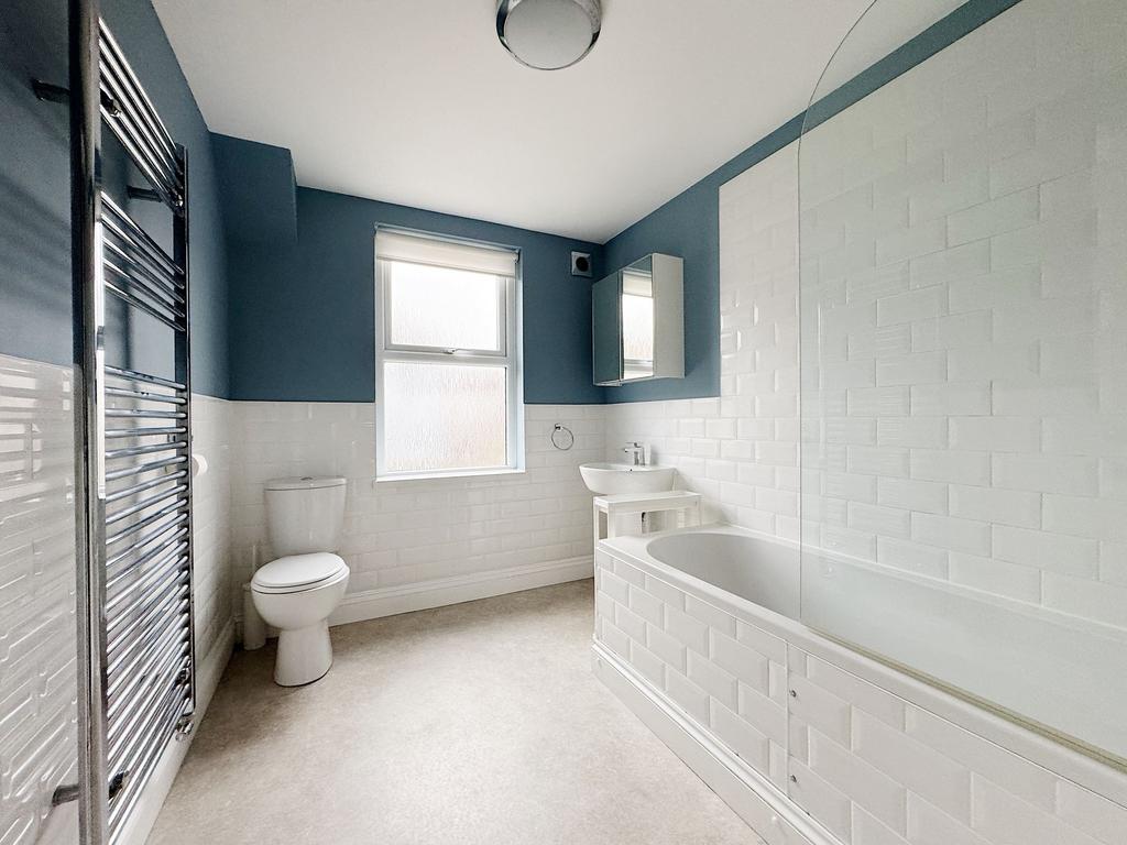 Bright, modern bathroom with a white tile-lined...