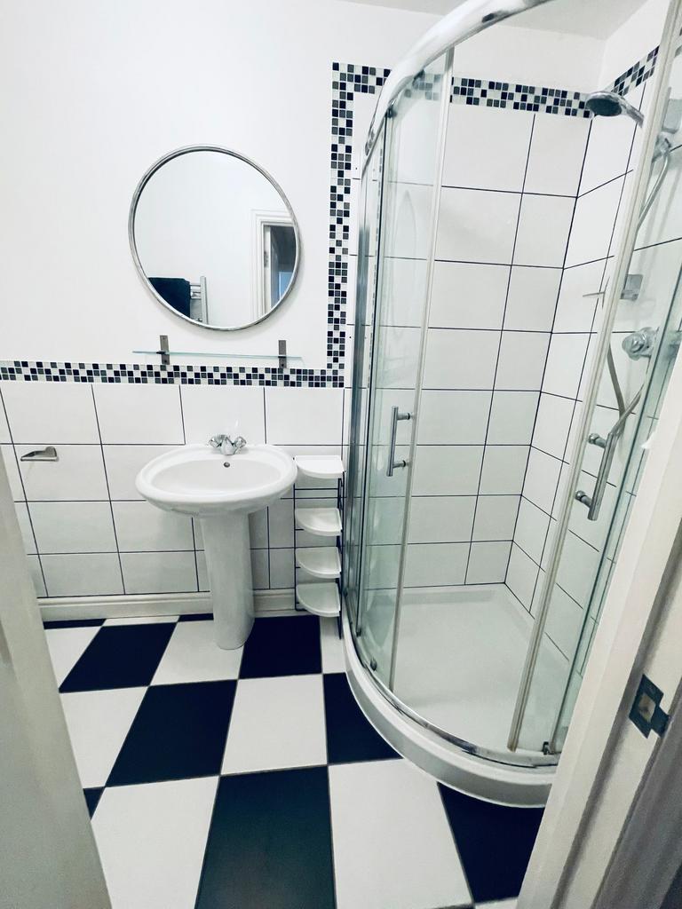Bright, modern bathroom with a curved glass sho...