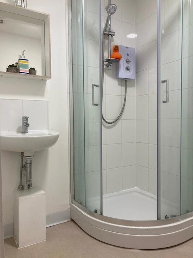 Bright, modern bathroom with a corner shower en...