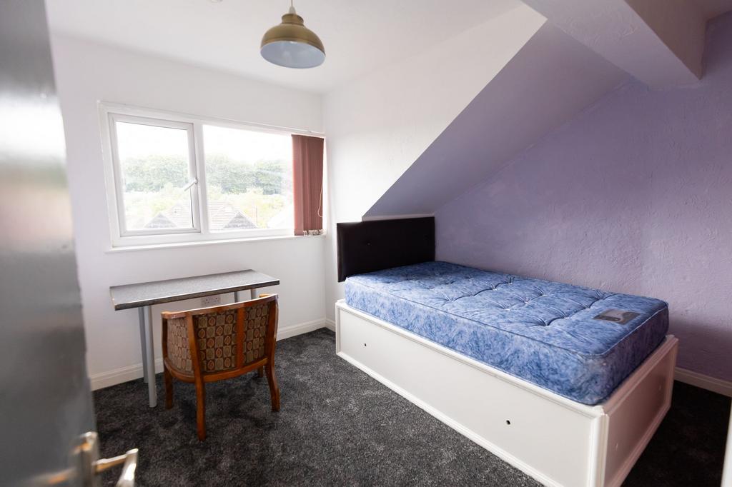 A cozy single bedroom featuring a bed with a da...