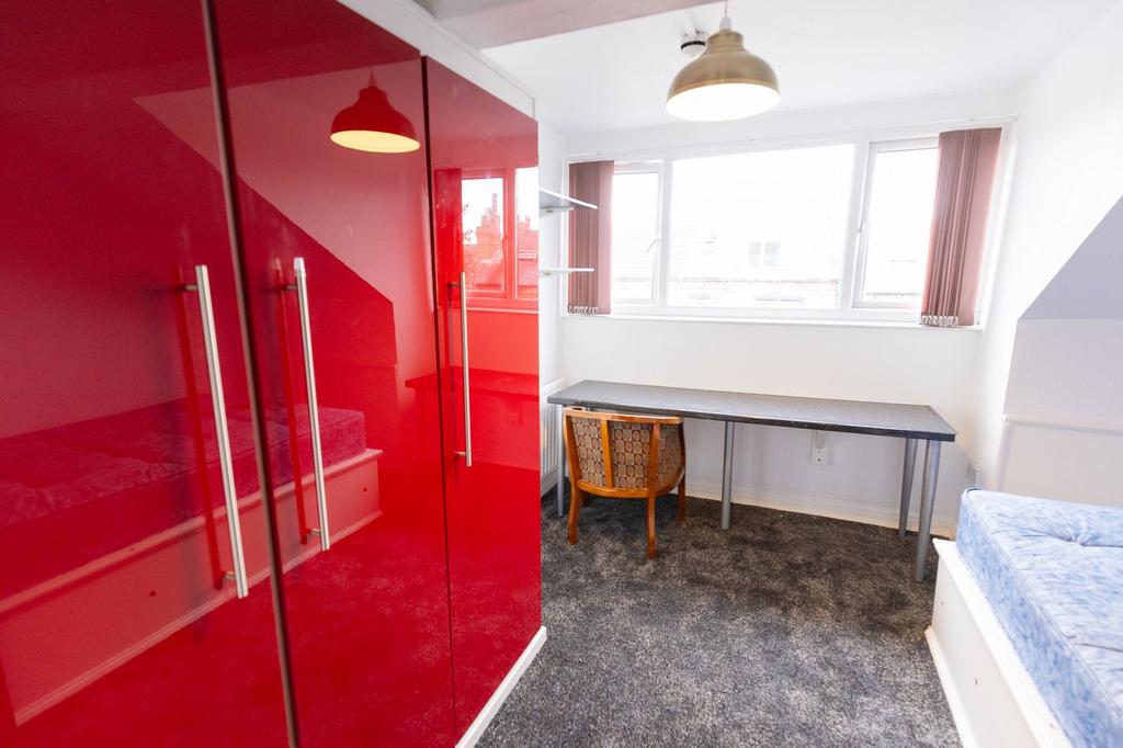 A bright, tidy bedroom featuring a large window...