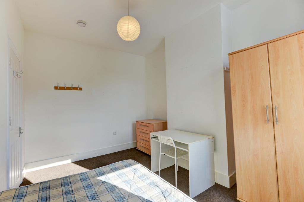 A bright and tidy bedroom featuring a comfortab...