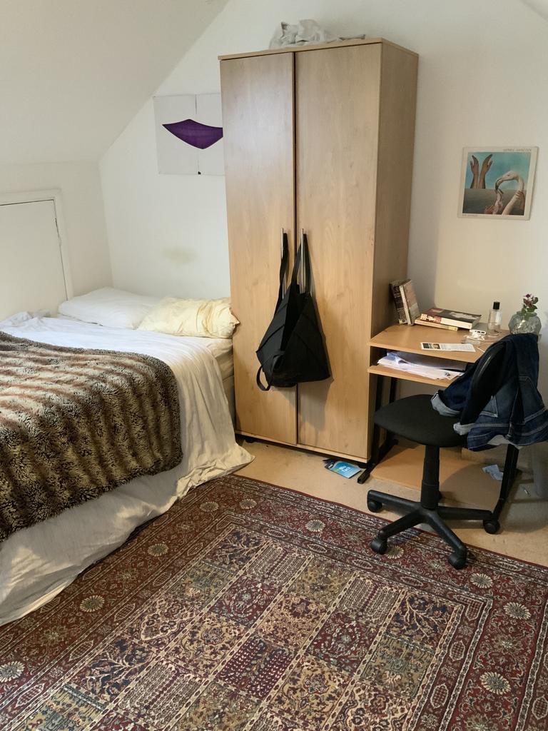 A cozy student bedroom featuring a bed with a p...