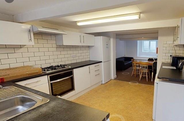 Bright, modern kitchen with white cabinetry, su...