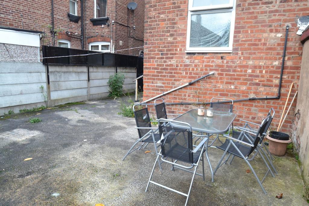 Paved private rear yard with brick boundary wal...