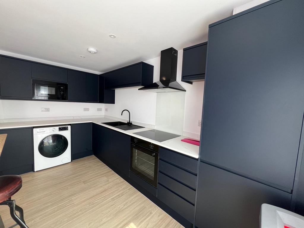 Modern fitted kitchen with dark navy cabinets, ...