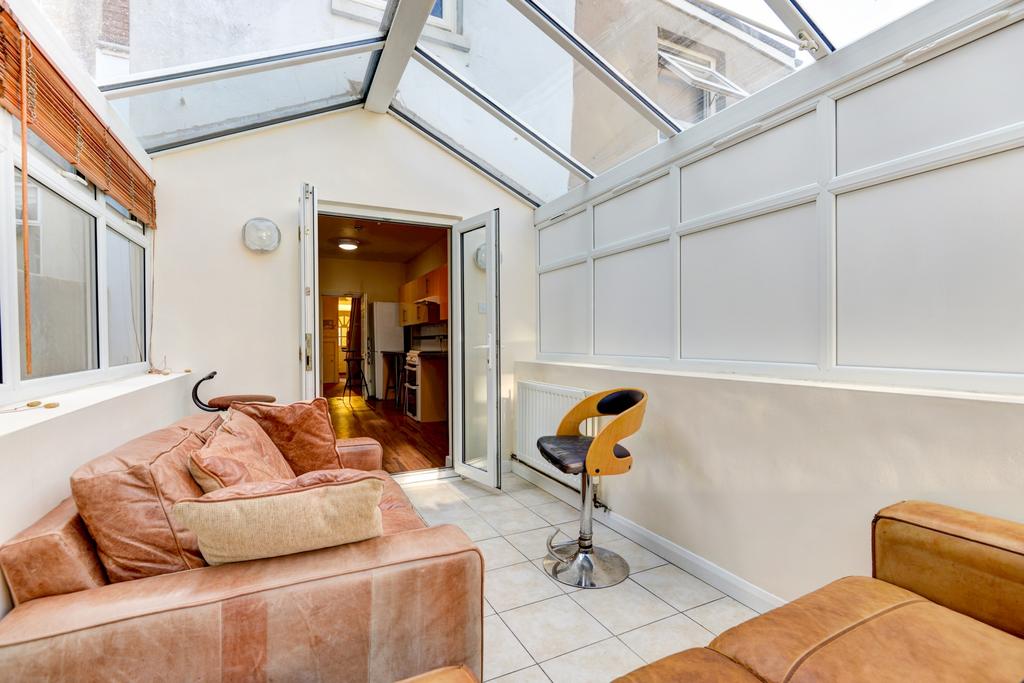 Bright, glass-roofed communal lounge with comfo...