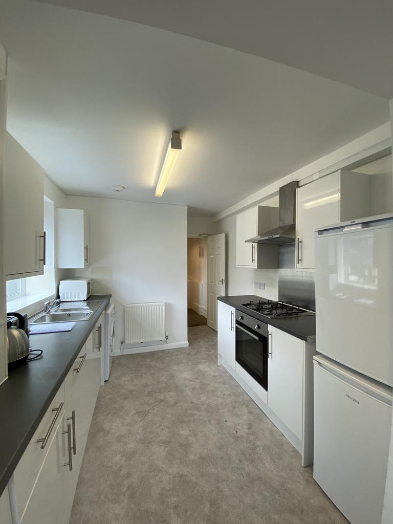 Bright, modern galley kitchen with white cabine...