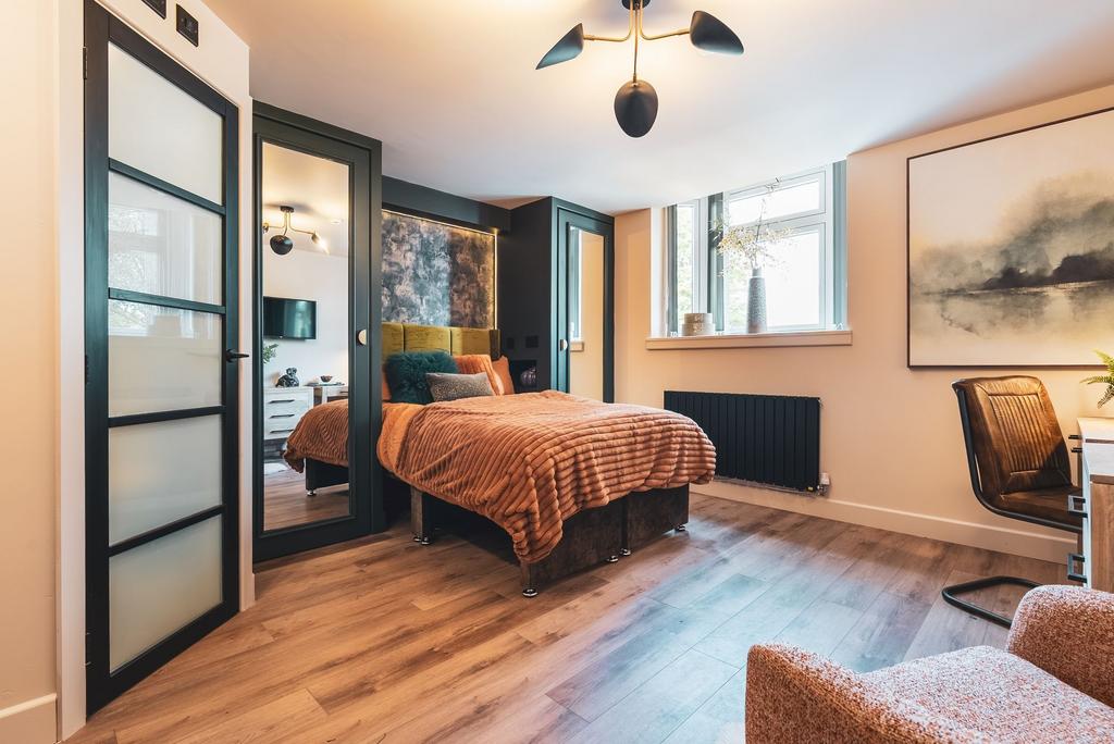 Well-styled double bedroom with warm wood floor...