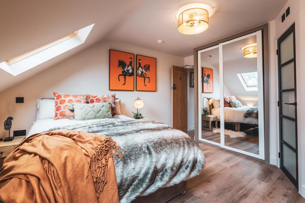 Stylish attic master bedroom with a plush bed d...