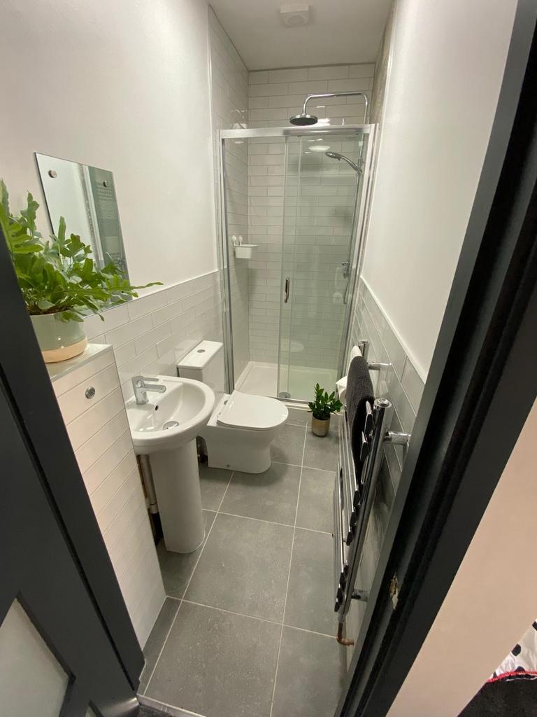 Modern tiled bathroom with a glass-enclosed sho...