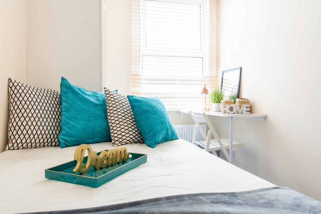 This cozy double bedroom features vibrant teal ...