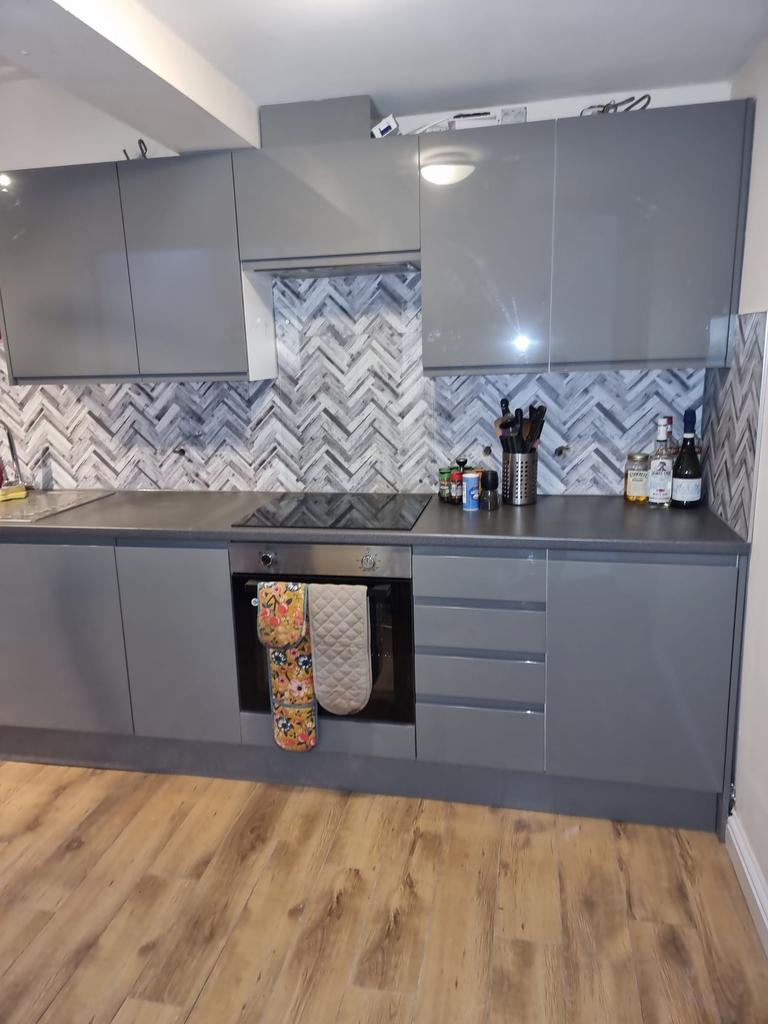Modern fitted kitchen with glossy grey cabinets...