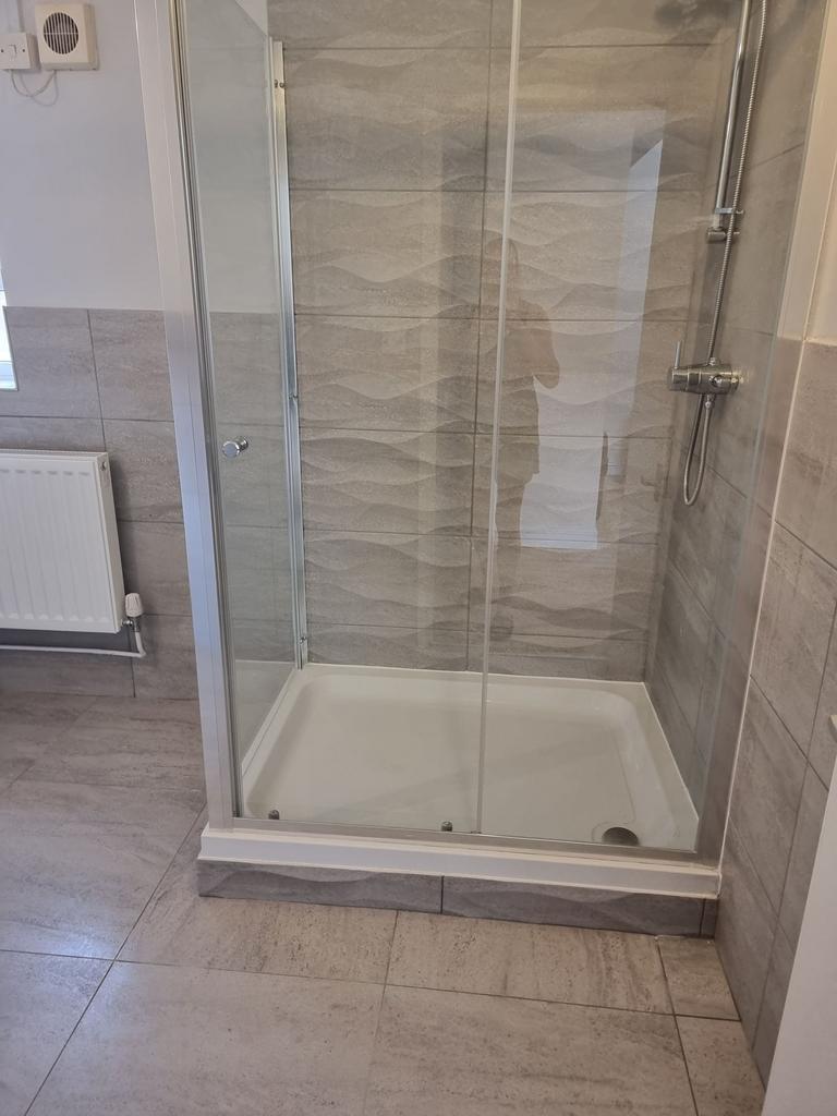 Modern tiled bathroom featuring a walk-in glass...