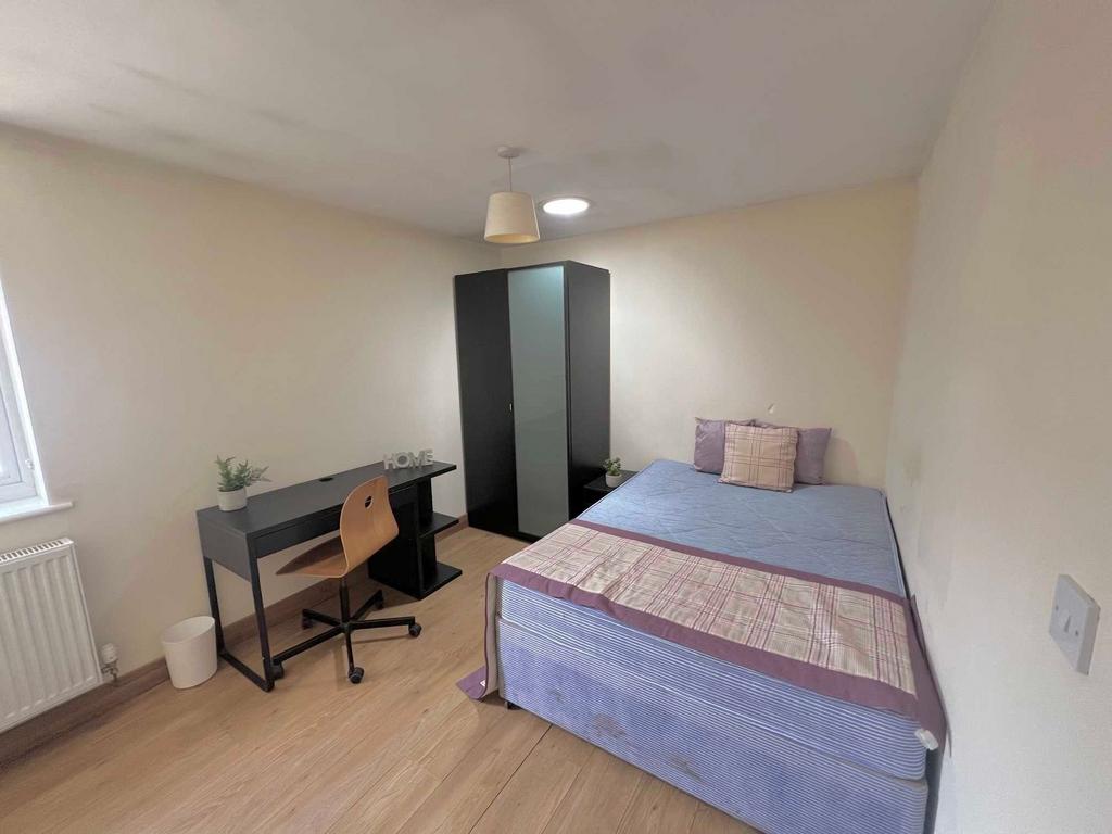 Bright, simply furnished bedroom with a double ...