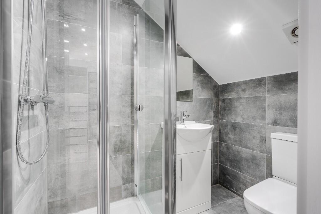 A modern, clean bathroom featuring a shower uni...