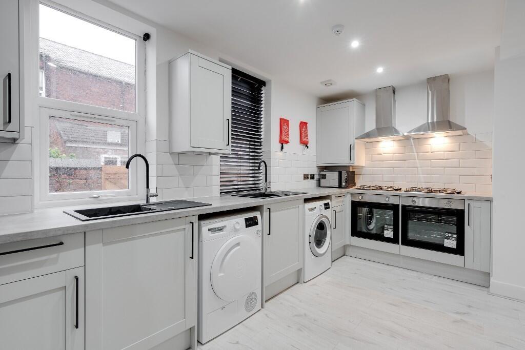A modern, well-lit kitchen featuring white cabi...