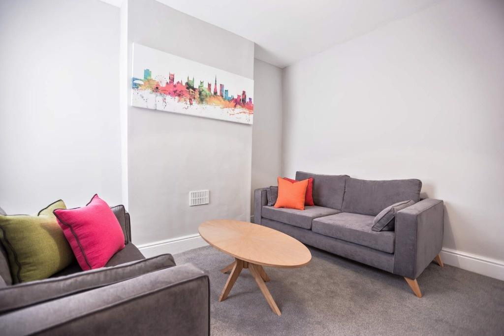 Bright, modern living room with matching grey s...