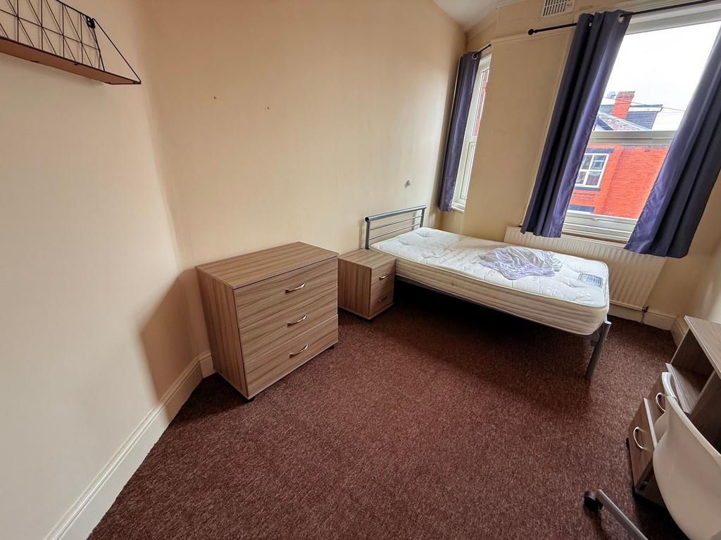 Bright furnished bedroom with a single bed by a...