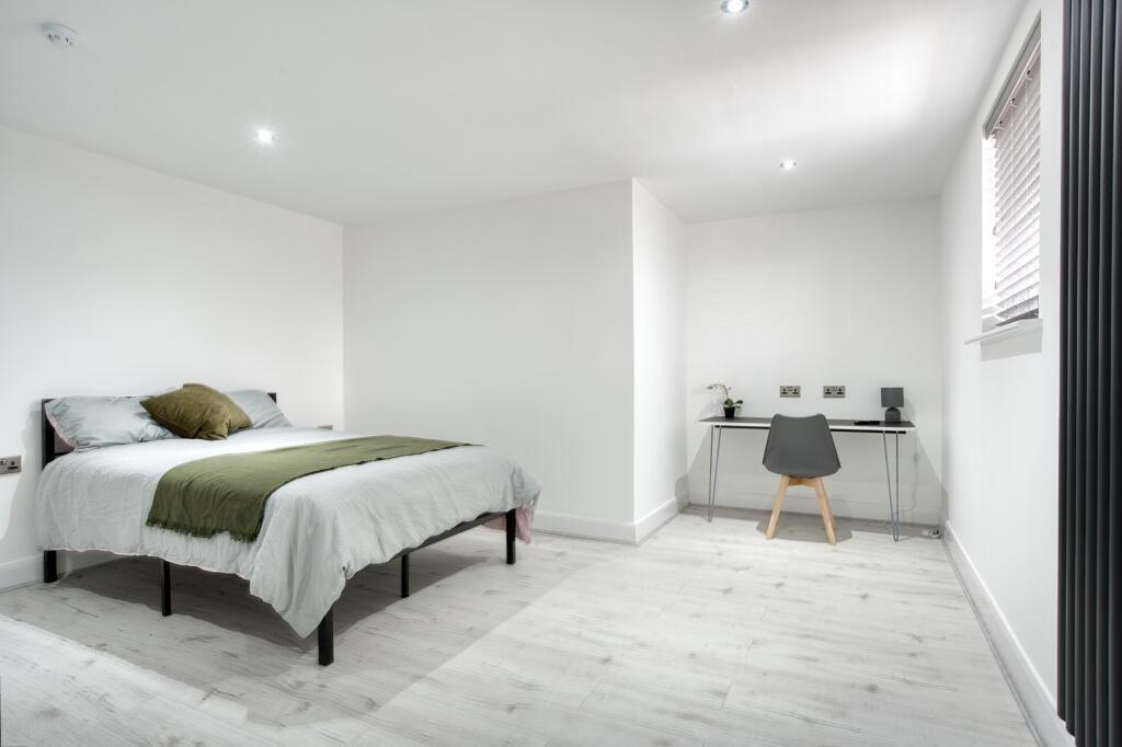 A spacious, bright master bedroom with a comfor...