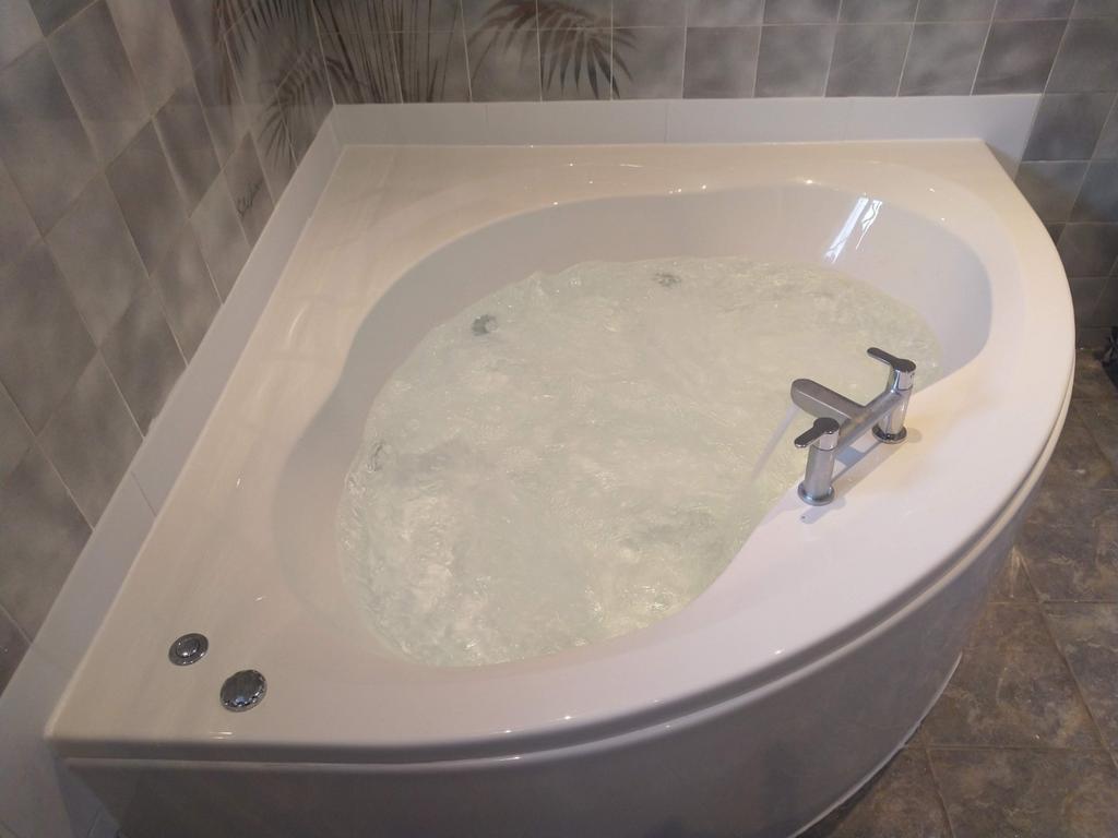 Modern corner whirlpool bath with chrome mixer ...