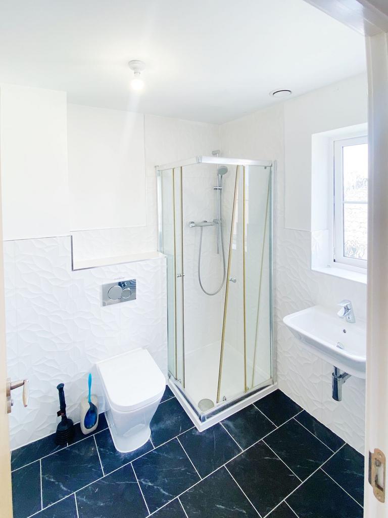 Bright modern bathroom with a corner glass show...
