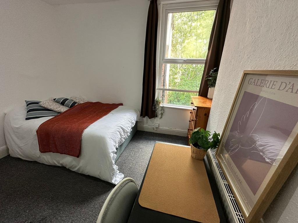 A cozy bedroom featuring a neatly made bed with...