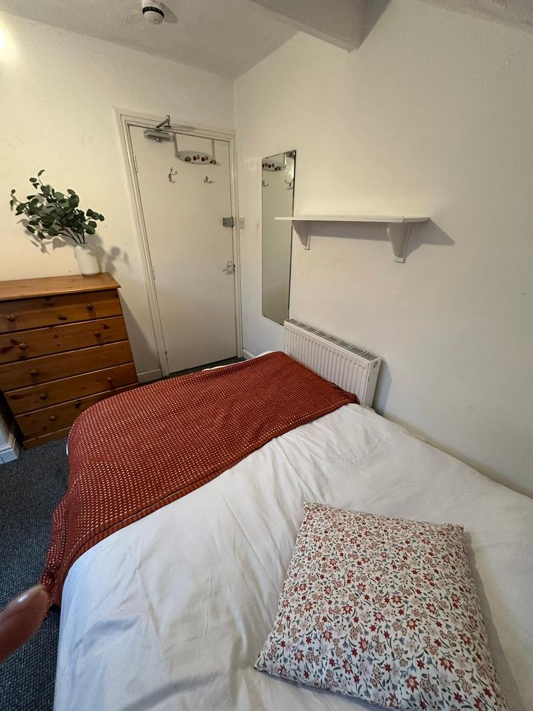 A modest bedroom with a neatly made bed featuri...