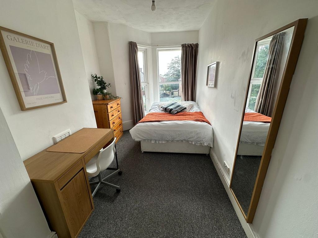 A well-lit, comfortable double bedroom with a c...