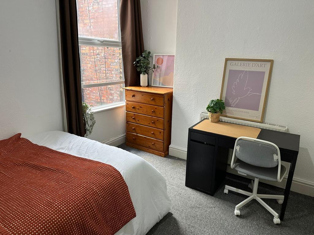 A cozy bedroom featuring a neatly made bed with...