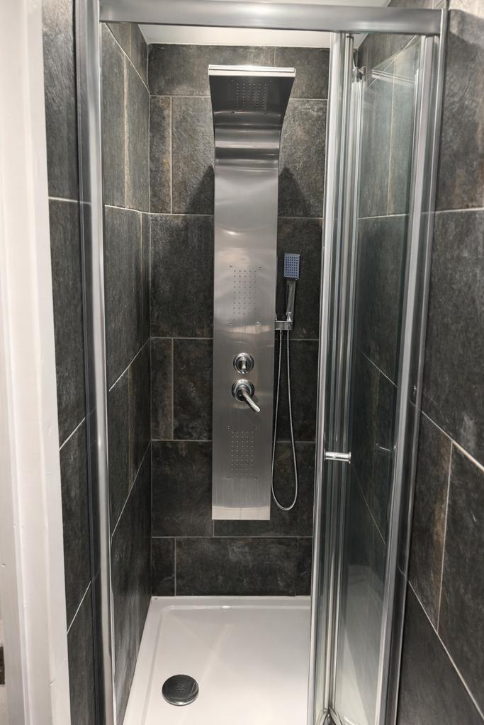 Modern tiled shower enclosure with sleek stainl...