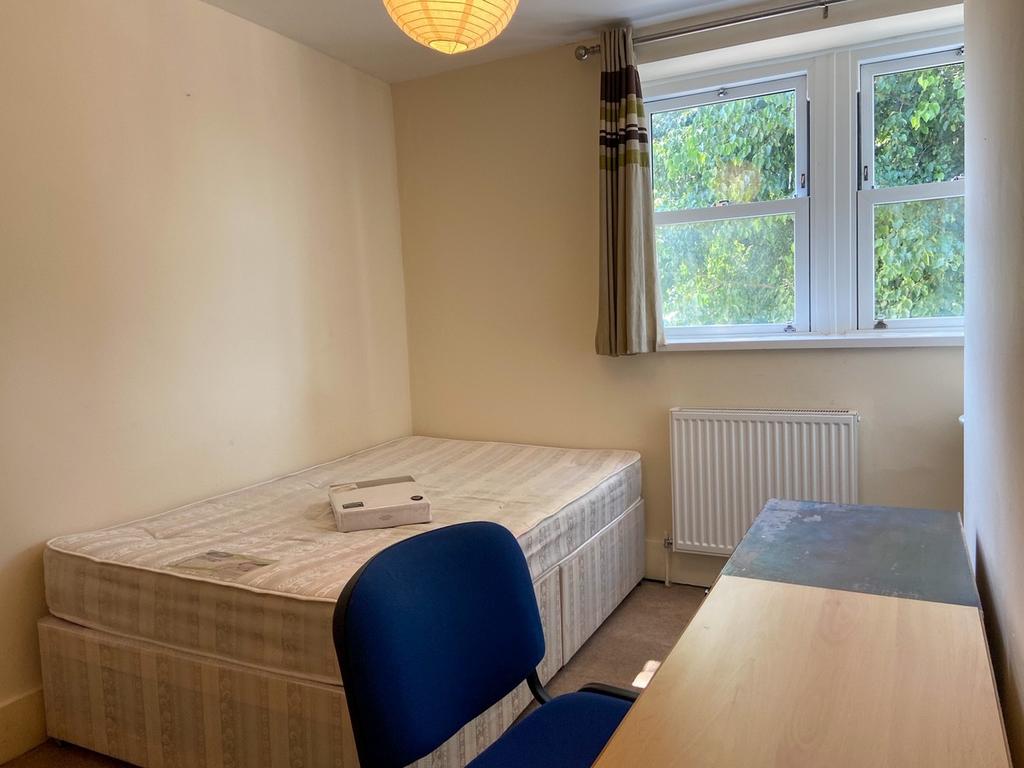 A well-lit, clean bedroom featuring a single be...