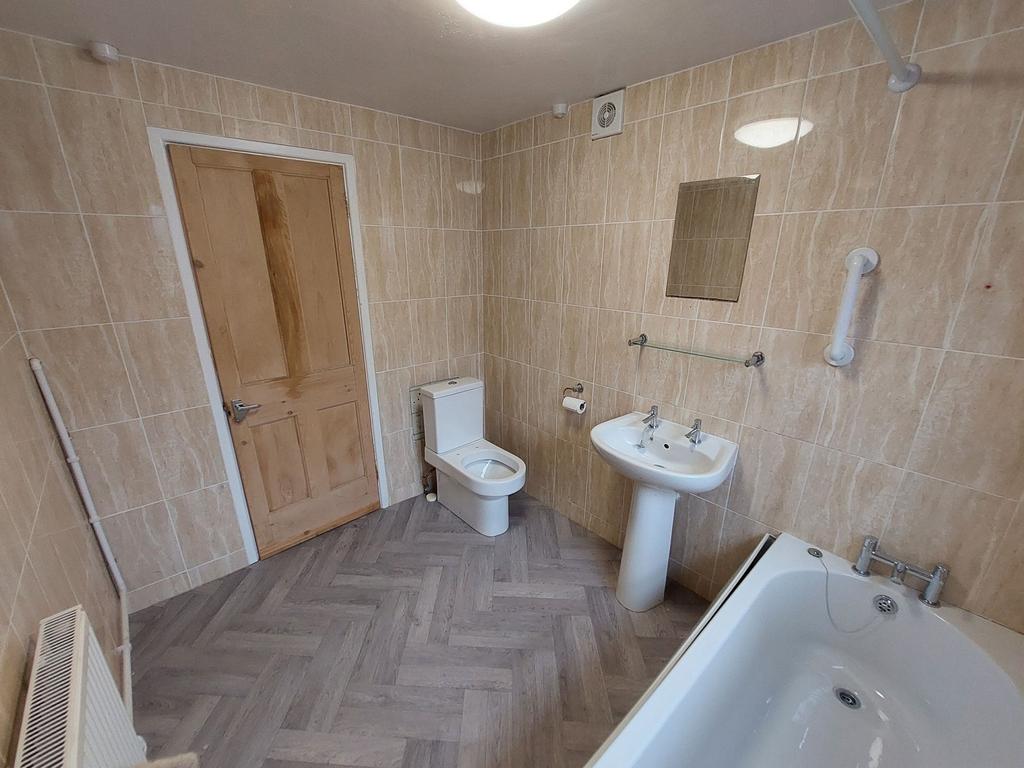 Bright, tiled bathroom with a modern white bath...