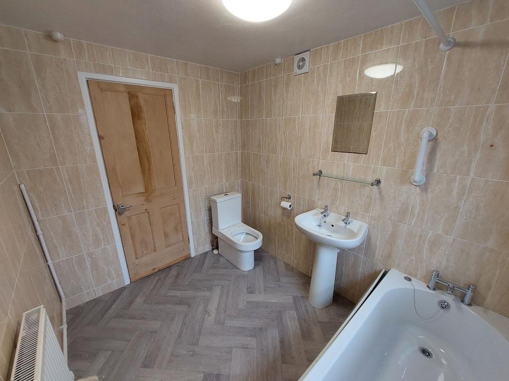 Bright, fully tiled bathroom with a bath, pedes...