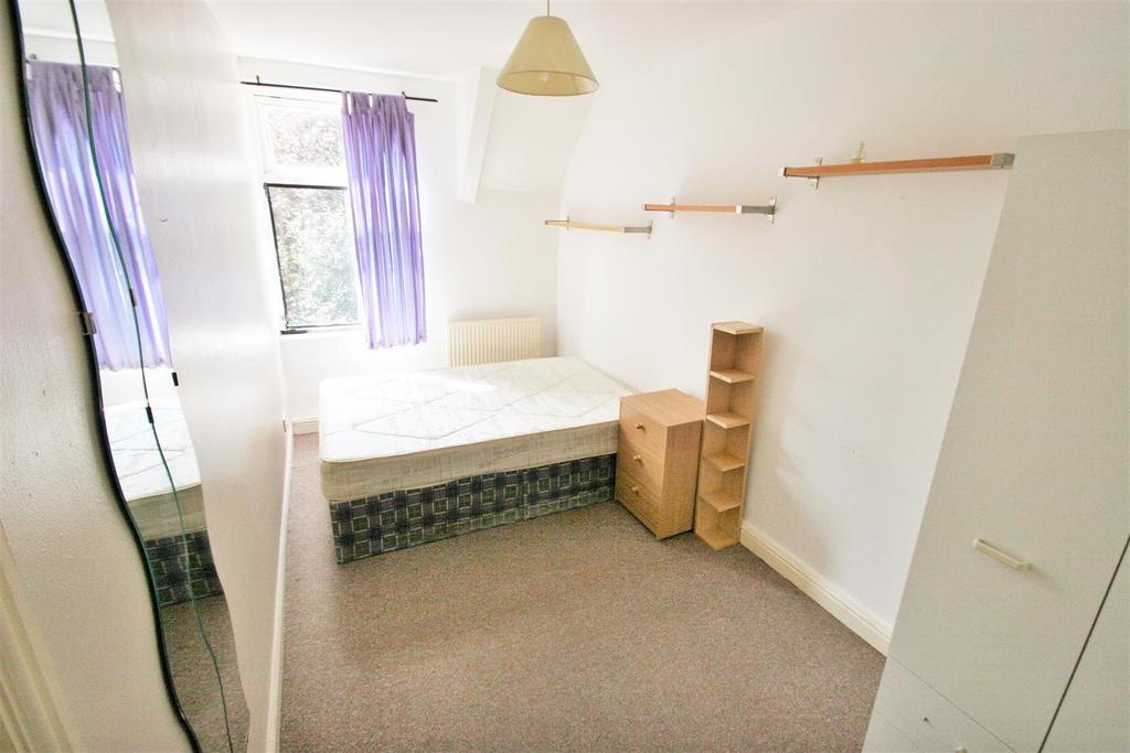A modest, well-lit bedroom with a single bed, a...