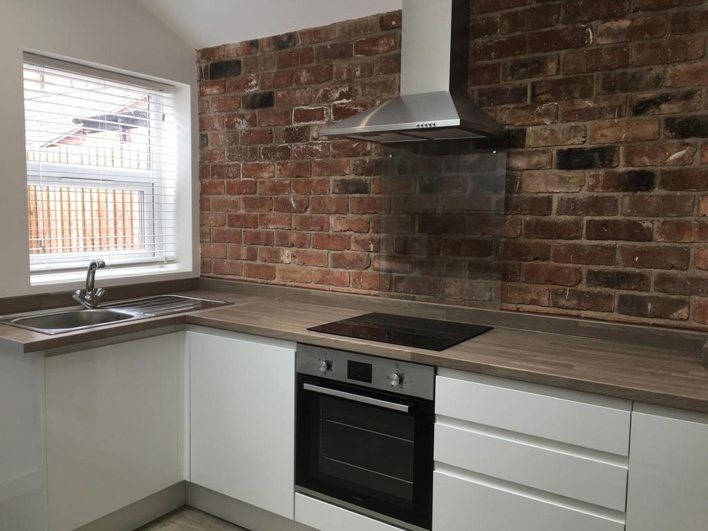 Modern fitted kitchen with white cabinetry, woo...